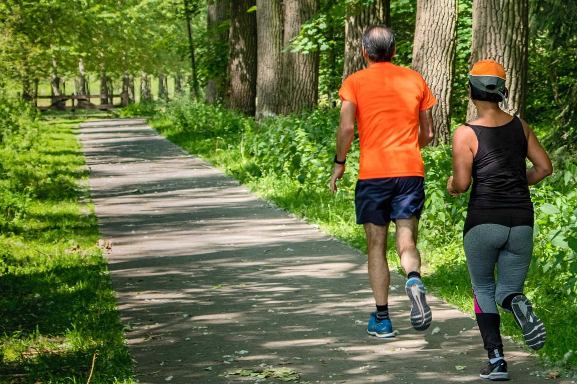 A group of healthy middle-aged runners jogging in the park.