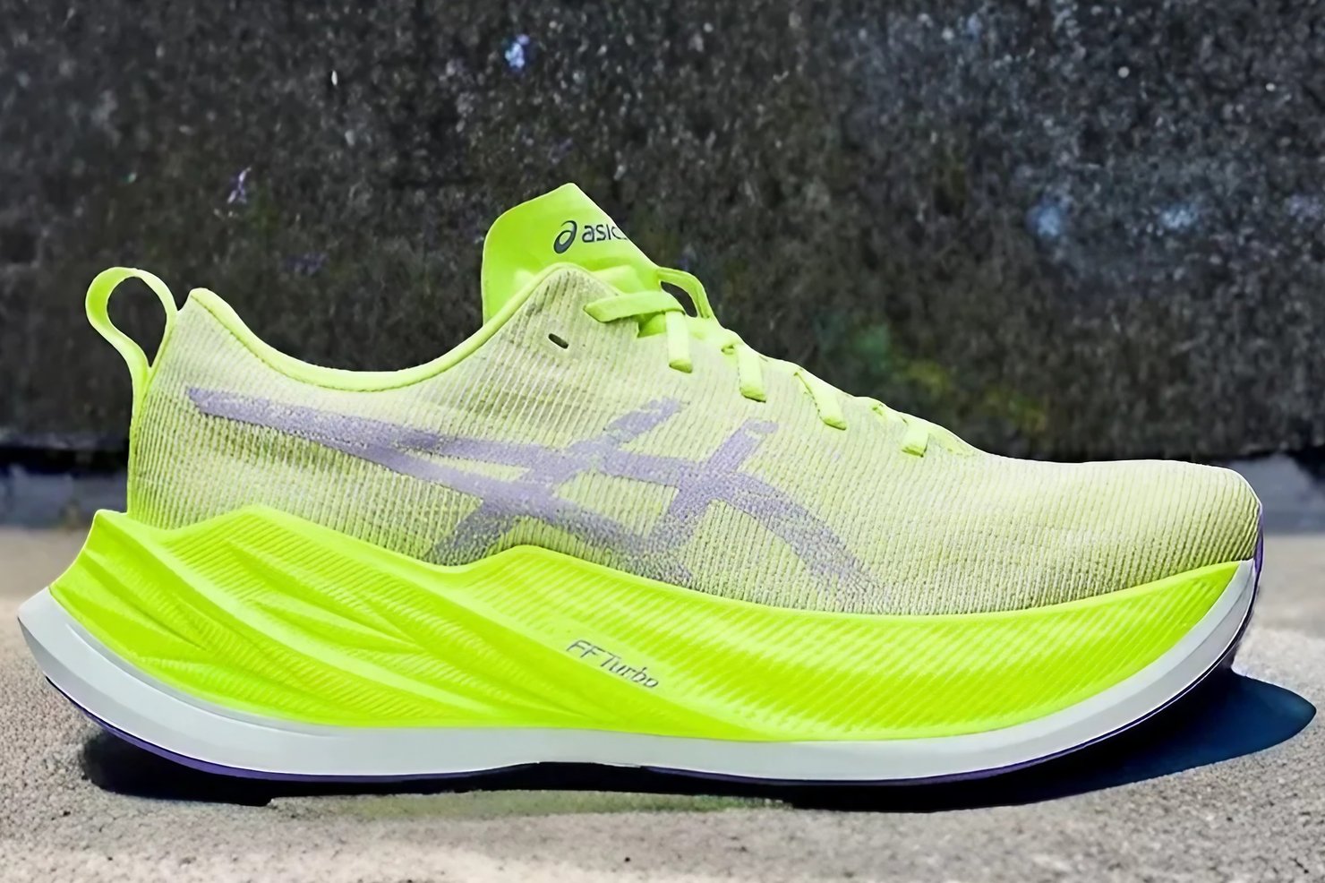 The Asics Superblast in front of a rock wall.