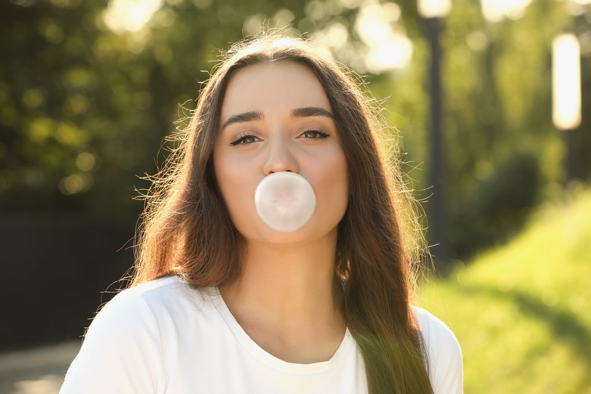 A woman is blowing a bubble of gum.