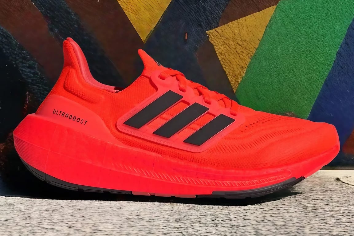 The Adidas Ultraboost Light is in front of a colorful wall.