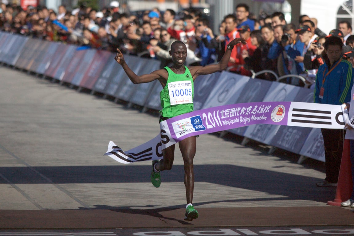 Skinny elite runner finishing the race with a smile.